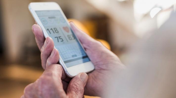 An individual holding a mobile phone showing their heart rate