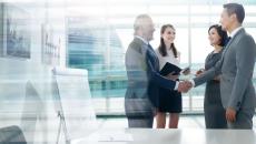 People standing in a room in front of a window while shaking hands