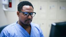 Healthcare provider wearing glasses, sitting in front of a computer monitor