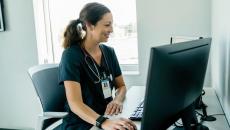 Person wearing nursing scrubs sitting at desktop