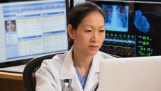 A doctor reading a patient's file on a laptop