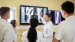 A group of clinicians discussing an X-ray report on a television screen