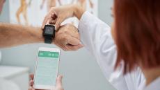 A doctor helping a patient synchronise their smartwatch with a mobile health app