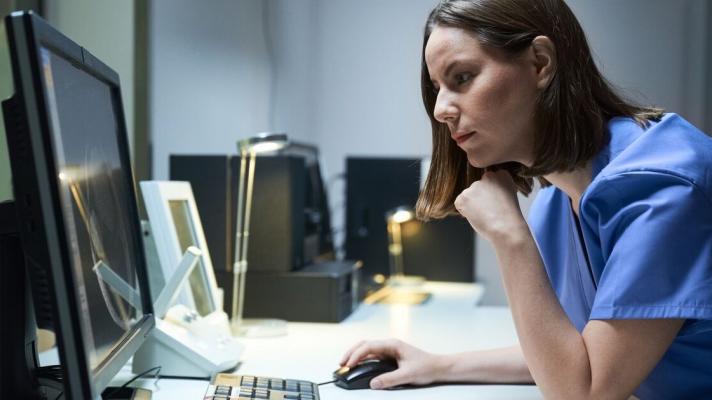 A clinician reading a report from a desktop computer.