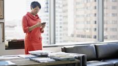 A person standing at her desk using a smartphone. 