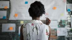 A woman at work standing in front of a wall with papers and planning documents