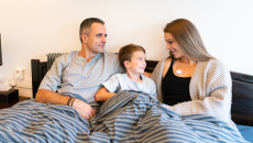 A family of three featuring a mother wearing the AeviceMD wearable stethoscope