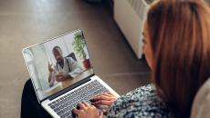 A person talking to a doctor via a video chat on a laptop.